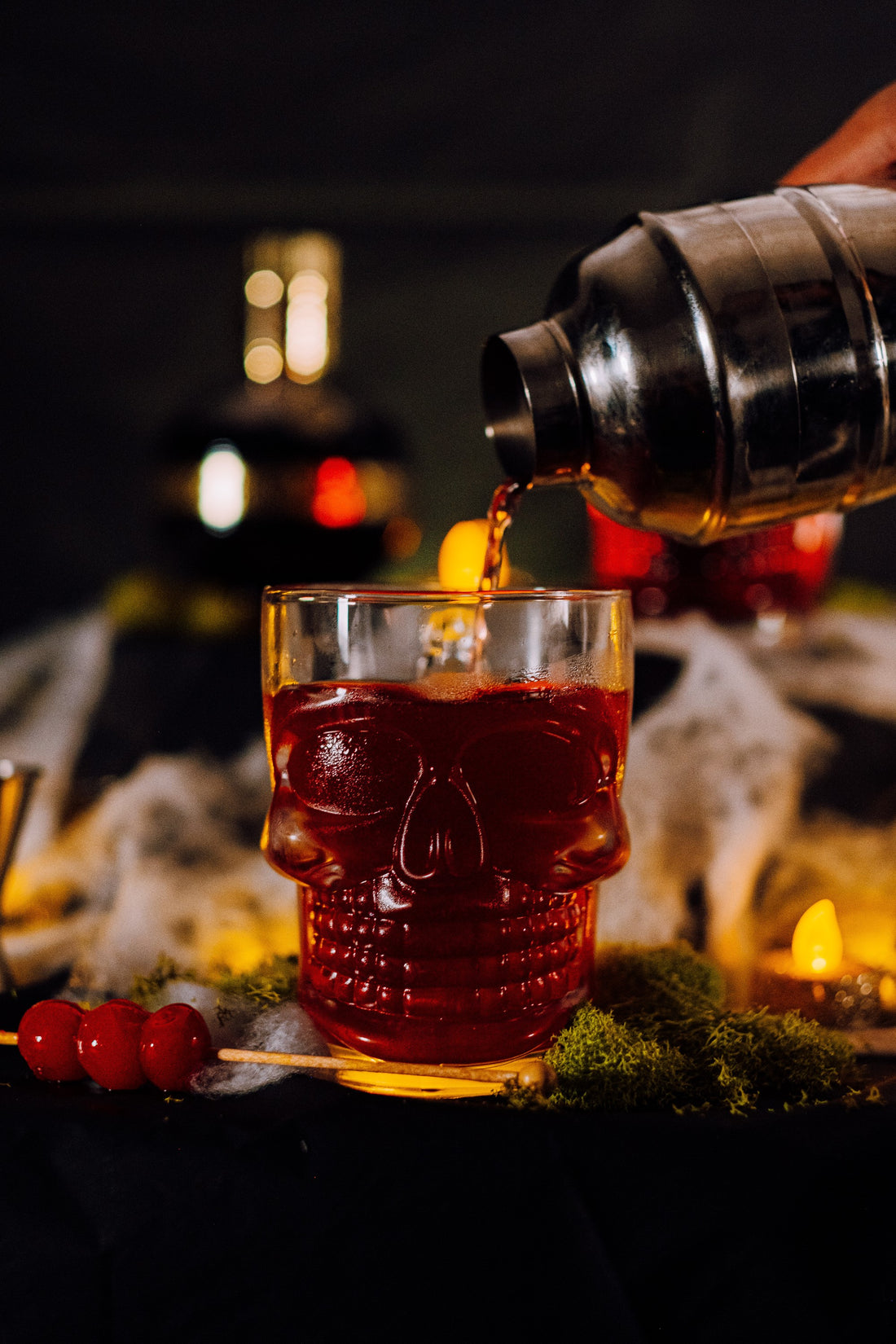 Bourbon cocktail poured into a skull glass. Features dark rich red colour and maraschino cherries.