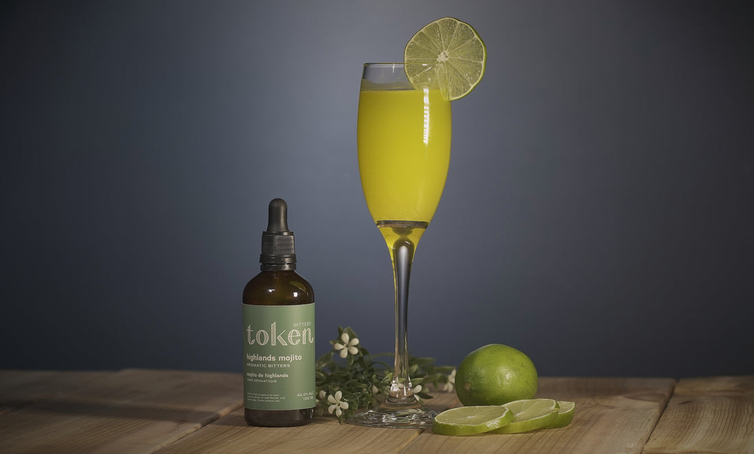 Key Limeade cocktail with a bottle of Token’s Highlands Mojito bitters and fresh lime slices 