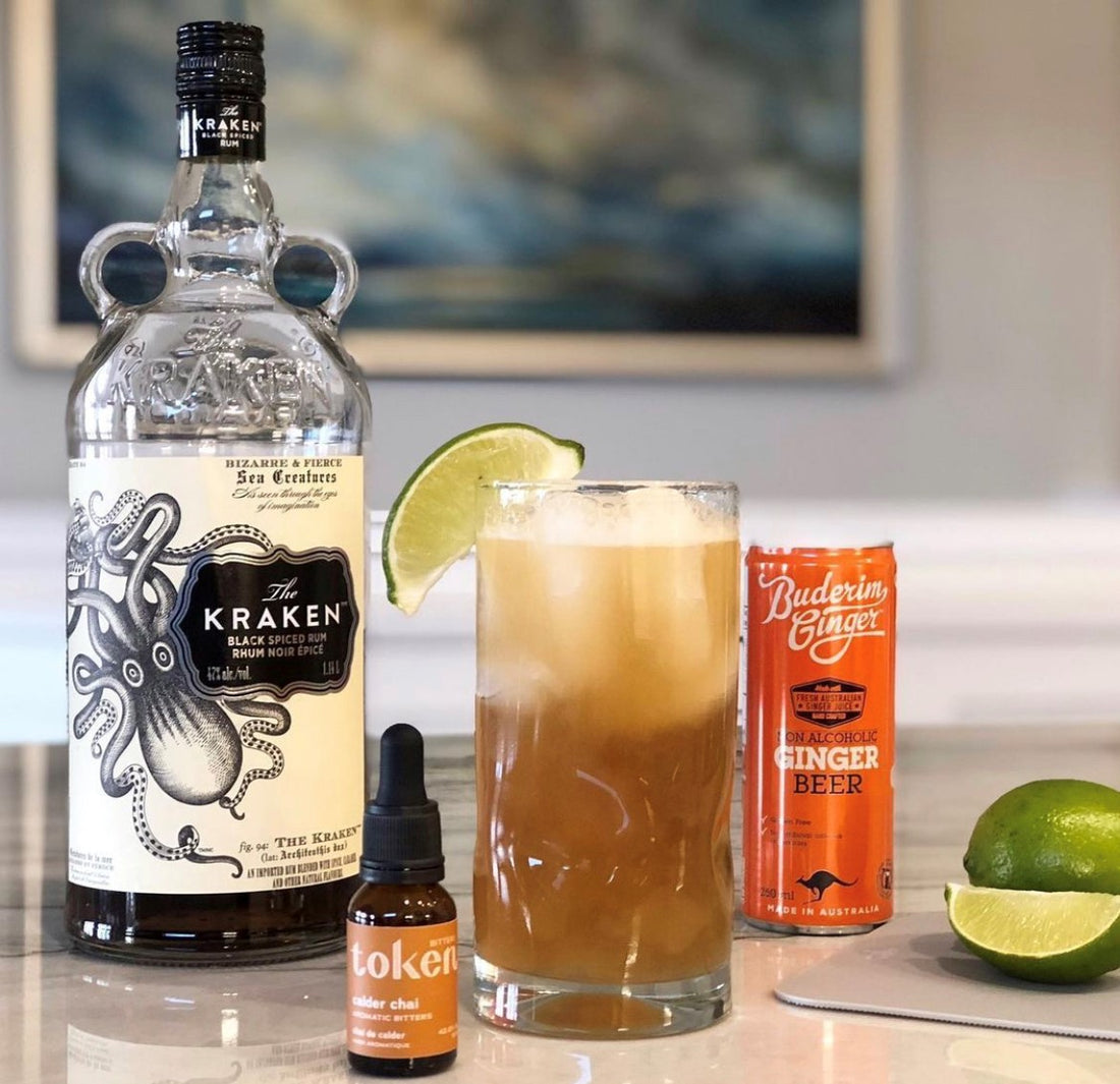 Dark and Stormy cocktail, made with Kraken Black spiced rum, ginger beer, and Token Chai Bitters. Cocktail is garnished with a lime