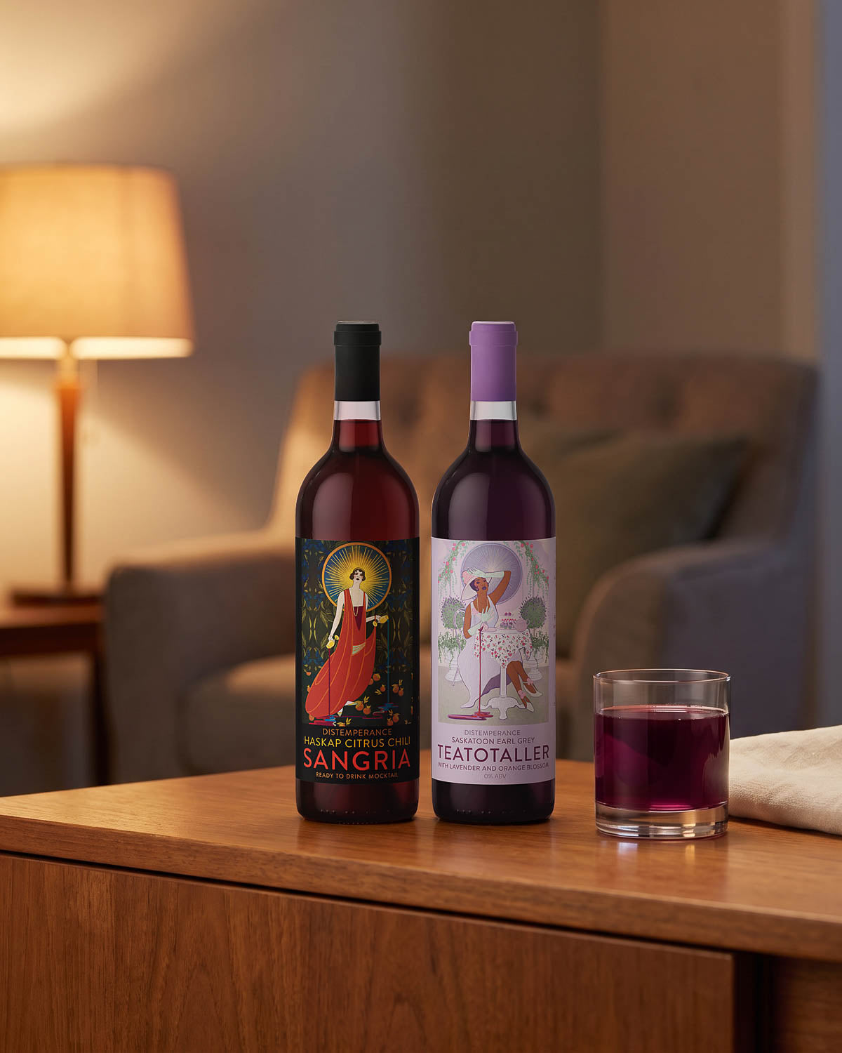 Two Token mocktail bottles on a sideboard beside a lamp with a poured glass