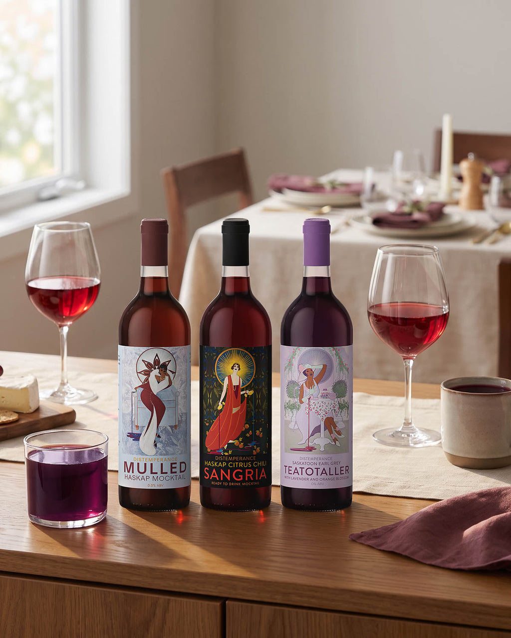 Three Token mocktail bottles on a hosting table with poured glasses and a cheese board